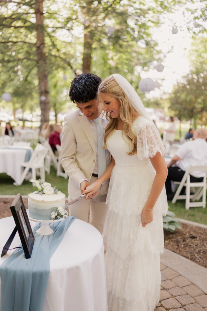 Shot of the bride and groom cutting their blue and white decorated wedding cake, taken by Robin Kunzler Photo