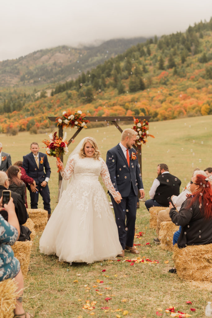 Bride and groom holding hands after the ceremony at the groom's father's ranch in Utah.