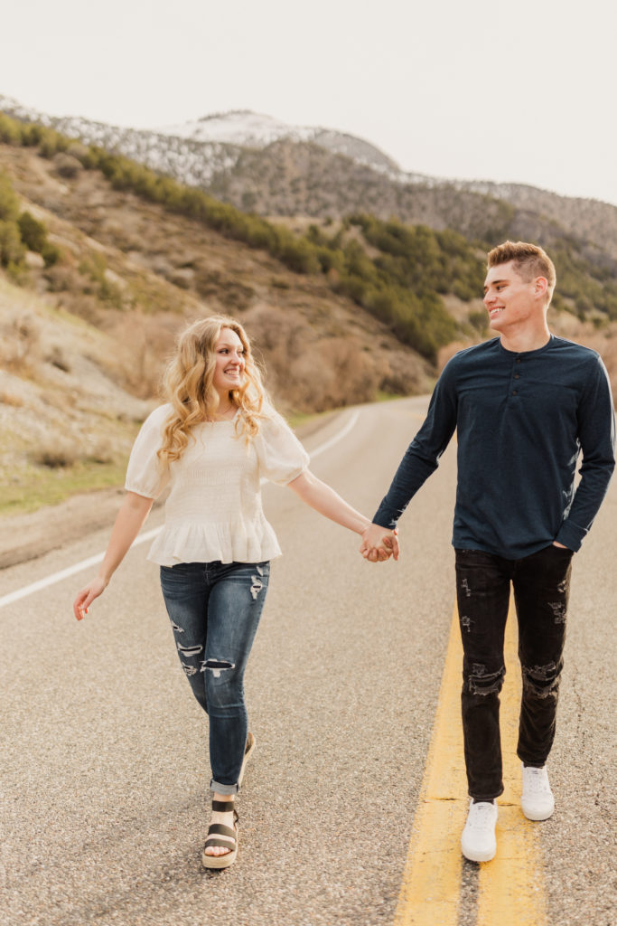 Getting Comfortable In Front of the Camera For Your Wedding Day: Couple holding hands as they smile at each other while walking in the middle of highway