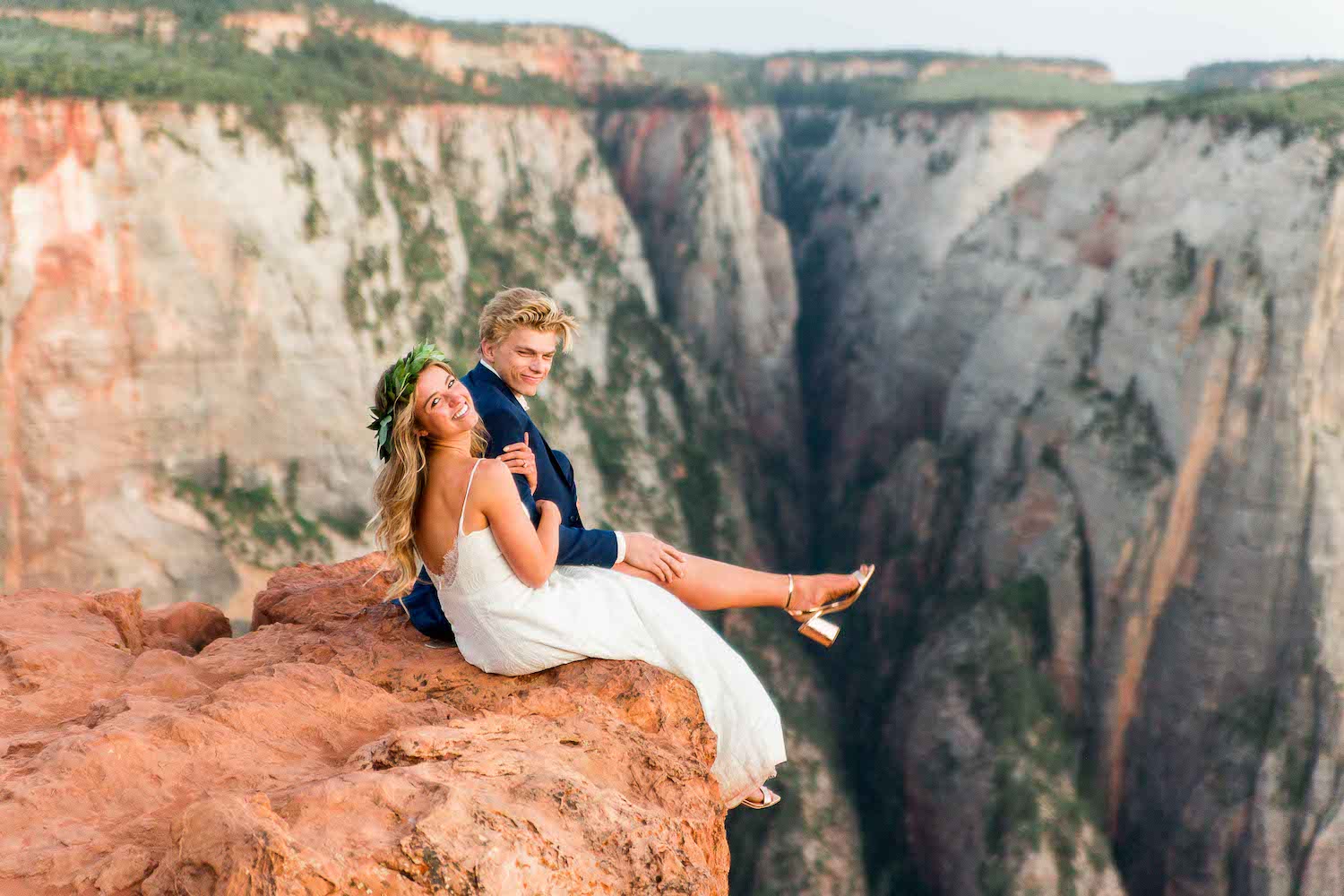 Bride and groom sitting on edge of a cliff during their wedding shoot with Robin Kunzler Photo