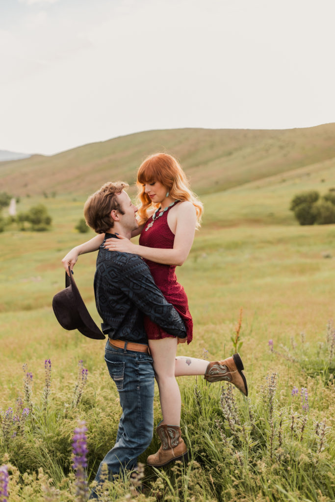 Jessica and Jayson embrace for a hug and look into each other's eyes as they are surrounded by wildflowers in the mountains for their engagement photos. Taken by Robin Kunzler Photo, Logan Utah Wedding Photographer.