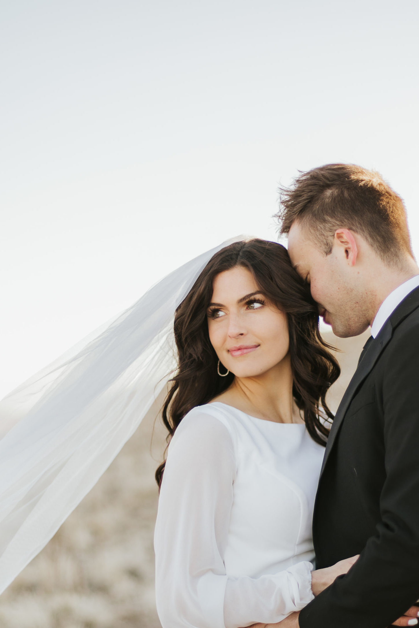 Bride looks off into the distance as couple share an embrace, captured by Robin Kunzler Photo