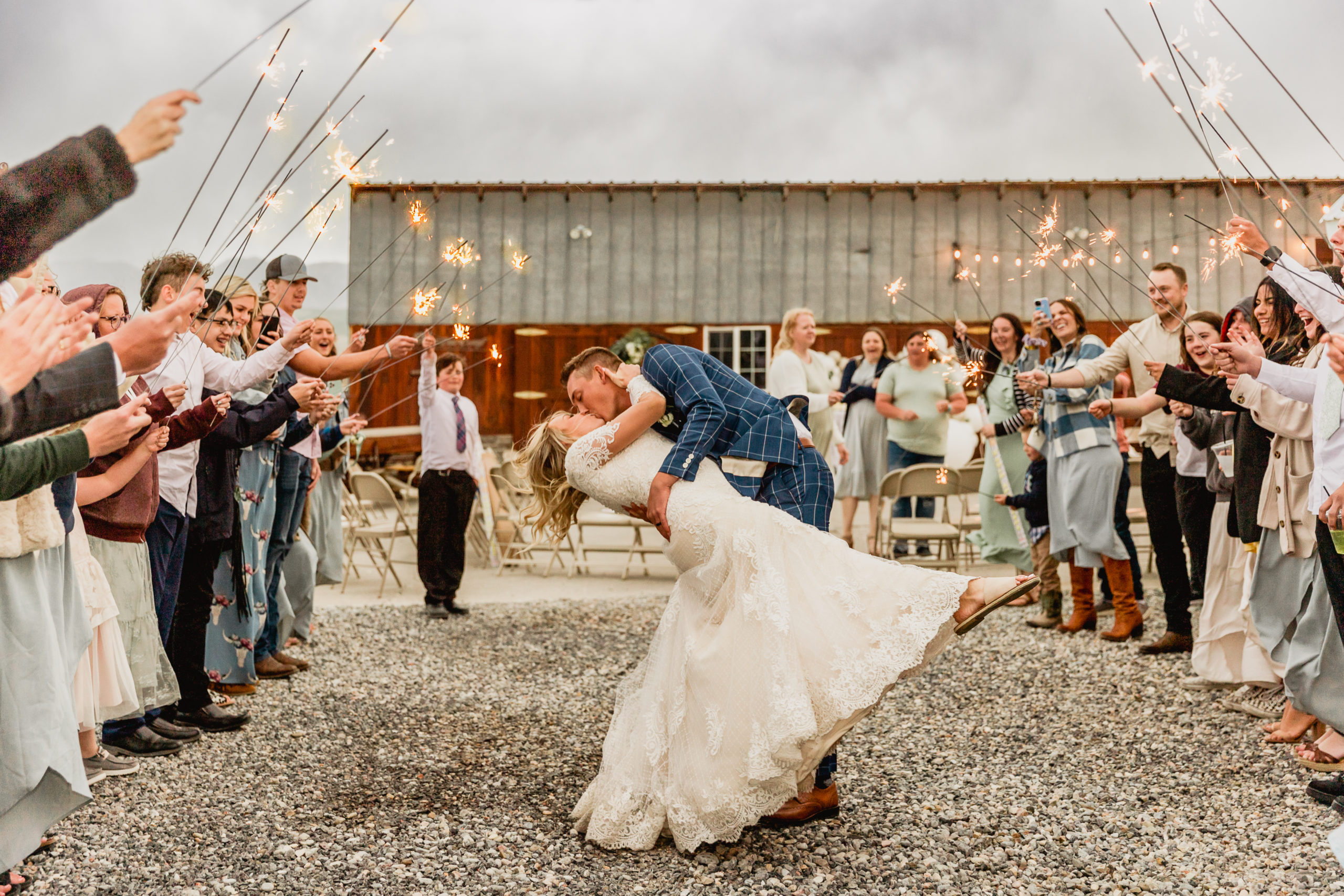 Bride and groom share a kiss as their wedding guests hold up sparklers, captured by Robin Kunzler Photo
