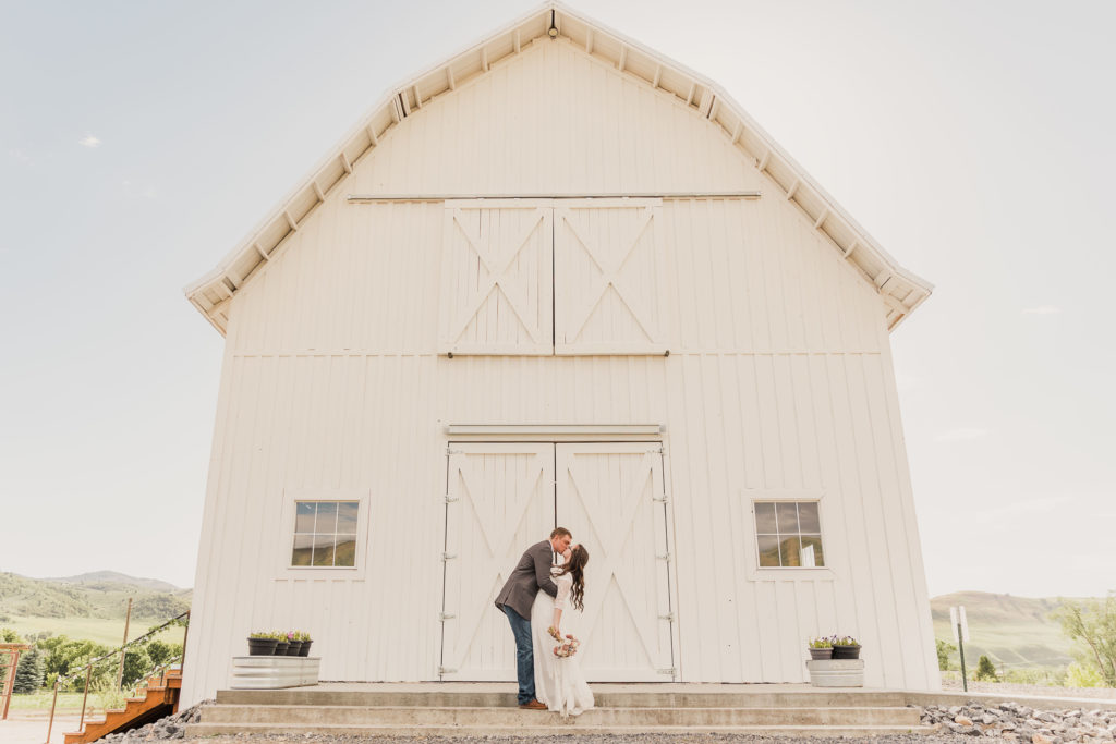 Bride and groom sharing a kiss in front of a barn, taken by Robin Kunzler Photo