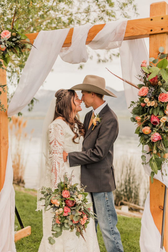 Newlywed couple posing in front of creative wedding arch, captured by Utah western wedding photographer Robin Kunzler Photo