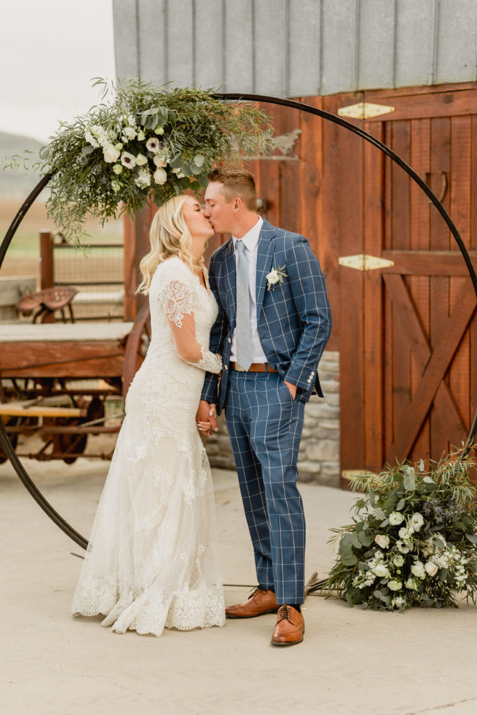 Bride and groom sharing a kiss in front of circular wedding arch during their Utah Wedding, shot by Utah western wedding photographer Robin Kunzler