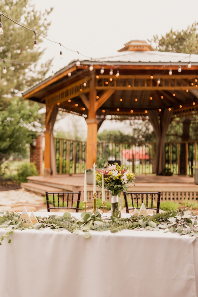 Wedding reception setup with floral centerpieces and gazebo behind it at The Hearthside Event Center
