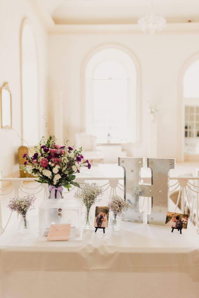 Close-up shot of wedding decor including floral arrangement and photos of bride and groom, taken by Robin Kunzler Photo