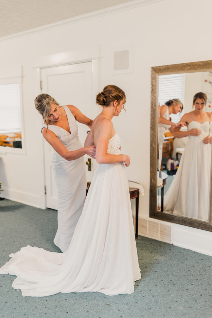 The bride's mother zipping up her dress in the getting ready room at the Hearthside Event Center in Utah
