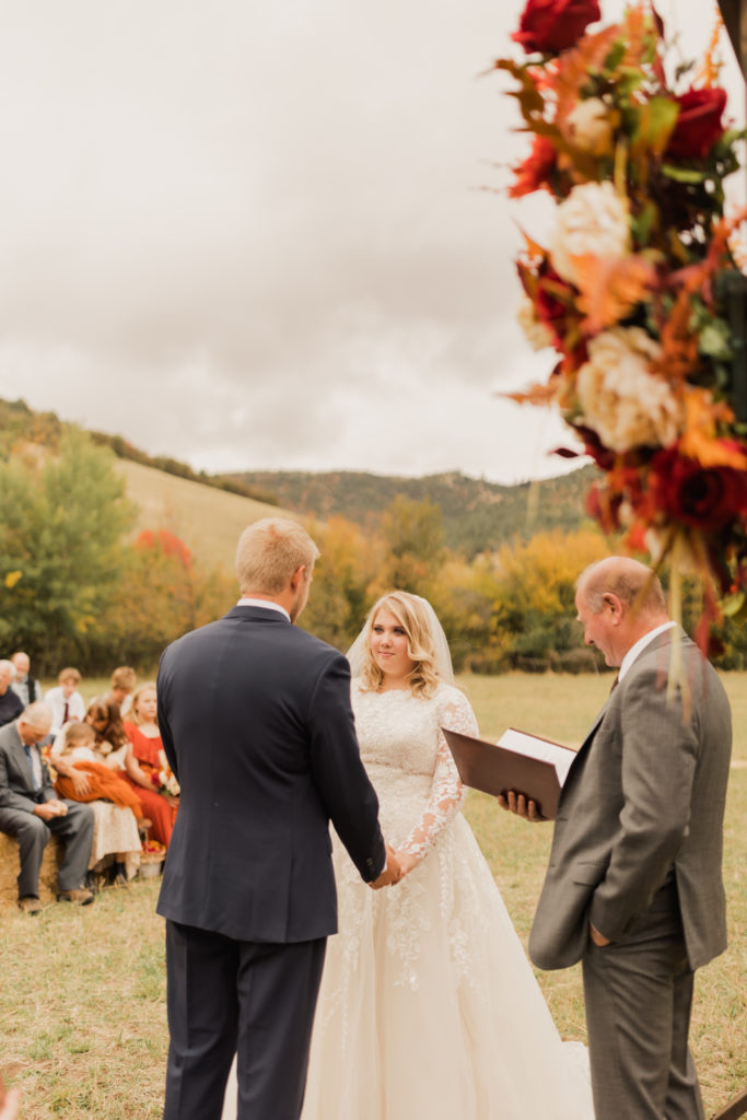 Bride and groom holding hands during the ceremony at the groom's father's ranch in Utah.