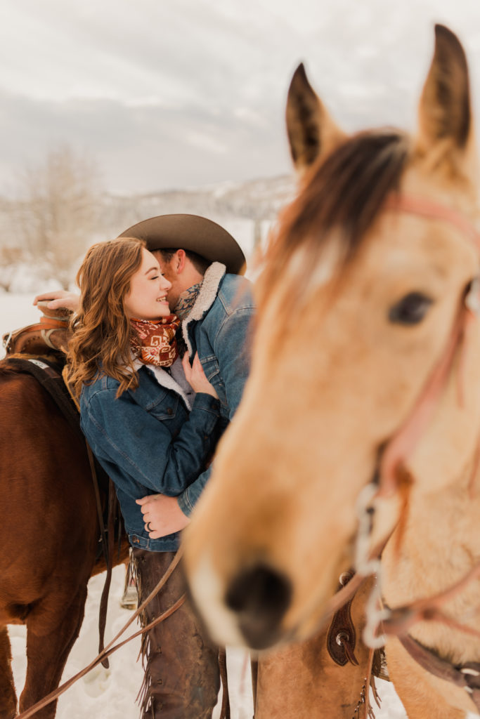 Western Couple photos of a couple smiling and flirting with the horses in the snowy mountains of Logan, Utah. Taken by Robin Kunzler Photo.