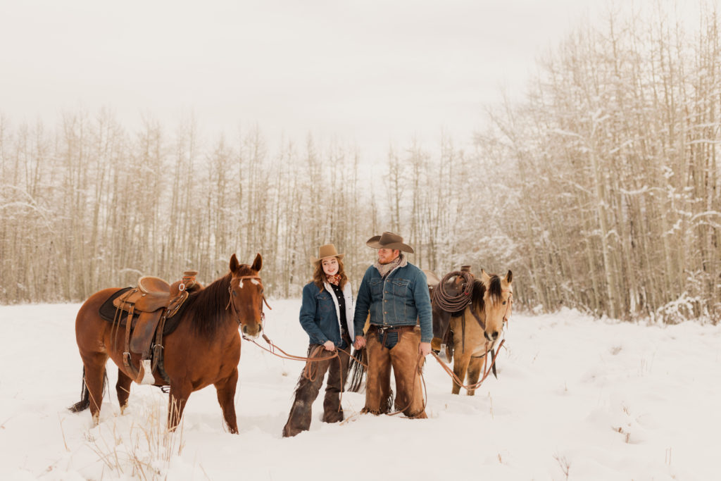 western engagement photo of lane and mia in the snow with their horses.