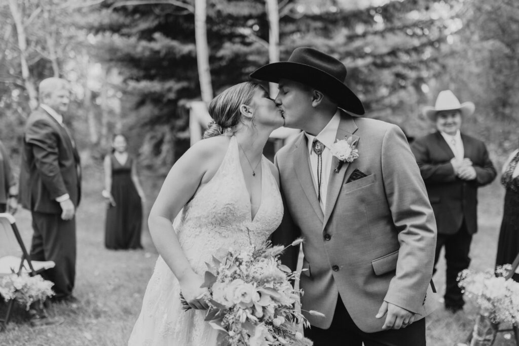 Yellowstone Elopement Photographer captures the couple kissing as they walk down the aisle at their Micro Wedding