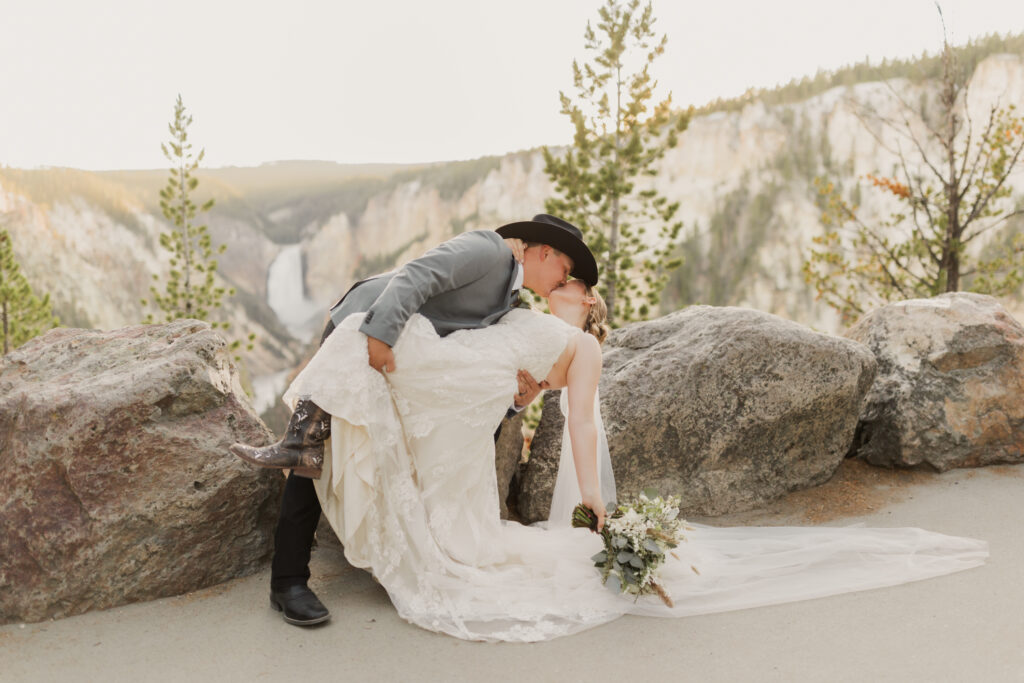 Yellowstone Elopement Photographer captures the couple dip kissing in front of Artist Point in Yellowstone National Park.