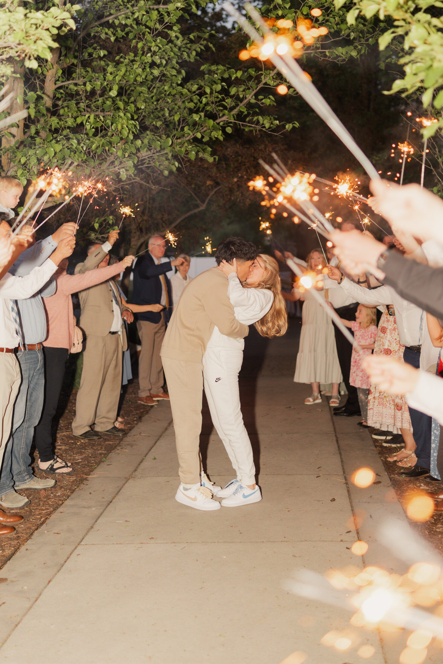 Bride and groom sharing a kiss as they exit the venue with bubbles flying in the air blown by their guests